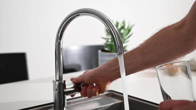 Fresh water running from a tap in a kitchen, there is a fruit bowl in the background, stock footage by Brian Holm Nielsen