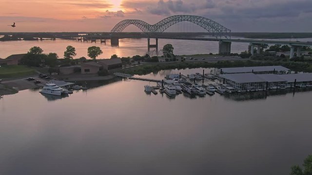 Aerial flying over Mud Island River Park to the Hernando de Soto Bridge crossing the Mississippi River at sunset. Memphis, Tennessee, USA