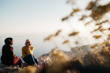 Lifestyle portrait of two best friends, smiling and having fun together. Outdoor photo of two young women, one with hijab, enjoying each other company with old city of Dubrovnik in background.