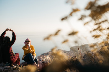 Lifestyle portrait of two best friends, smiling and having fun together. Outdoor photo of two young women, one with hijab, enjoying each other company with old city of Dubrovnik in background.
