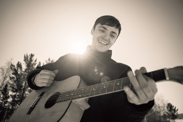 handsome guy playing guitar outside in sunny winter day