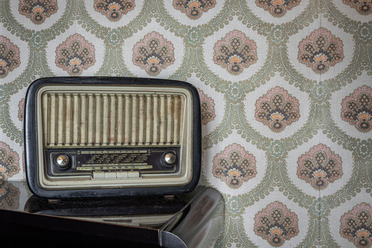 March 1, 2020 - Rome, Italy - Telefunken Mignonette, an old transistor radio, with knobs and buttons for manual tuning. In the background a vintage wallpaper. Ancient object, worn and ruined by time.
