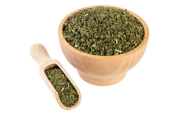 dried nettle herb or in latin Utricae folium in wooden bowl and scoop isolated on white background....