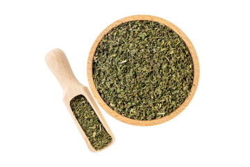 dried nettle herb or in latin Utricae folium in wooden bowl and scoop isolated on white background....