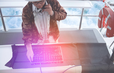 Dj mixes the track playing on the party in yacht. Asian men DJ in the party, DJ remote control, Man...
