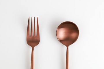 Rose gold colour fork and spoon on white background. Top view