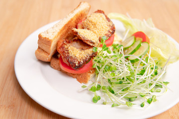 Vegan sandwich for breakfast, healthy & delicious food for plant based, vegan and vegetarian diet. Ingredients are toasted bread, vegan cheese, fried tofu, tomato, iceberg lettuce and kaiware sprouts.