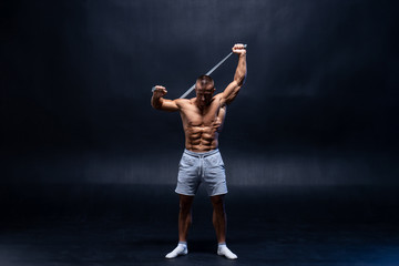 Fototapeta na wymiar Muscular man doing calisthenic exercise with power band isolated on the black background