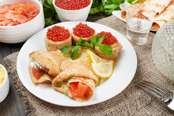 Russian pancakes (blini) with fresh sour cream, red caviar, red fish and a sprig of parsley on a...