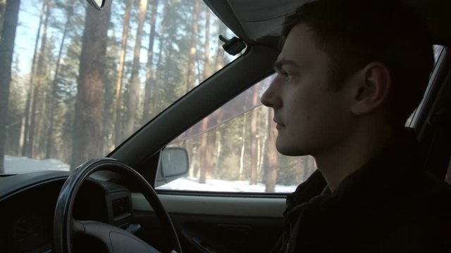 handsome guy driving a car through a forest