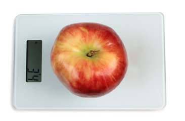 Big red apple on a kitchen scale on white background