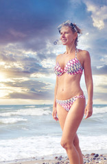 blond woman standing on the beach in bikini and with swimming goggles