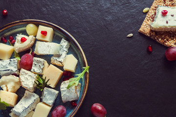 Obraz na płótnie Canvas Top view cheese plate assortment various types cheese and grapes with pomegranate seeds and crisp bread cheese dark background
