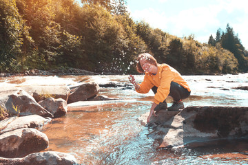 tourist girl sitting on the bank of a mountain river