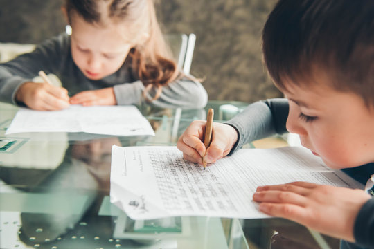 Schoolboy and schoolgirl writing letters. Close-up  pencil in the hand of child. Children learning to write letters at the table.