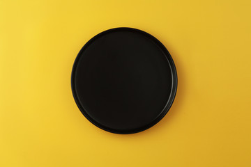 Empty plate on coloured background, top view