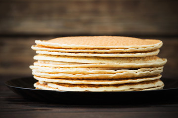 pancakes on plate on old dark wooden background