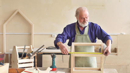 gray- Haired man by profession a carpenter working in his workshop. Portrait of an old carpenter.