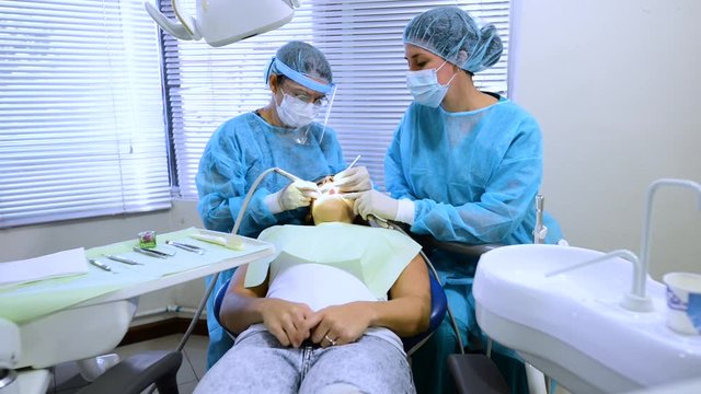 Two professional dentist working in a youn woman mouth