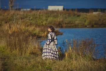 beautiful girl in a suit of the 19th century walks in the village