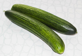wo fresh whole cucumbers on a light background.