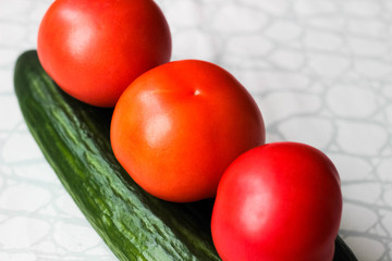 Fresh cucumbers and tomatoes as a whole on a light background.