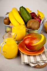 Fresh mango juice. Fruit basket on the table. Refreshing summer drink, orange juice. A glass on the table. Fruits are banana, kiwi, avocado and others. Vitamin nutrition. Vegan Food. 