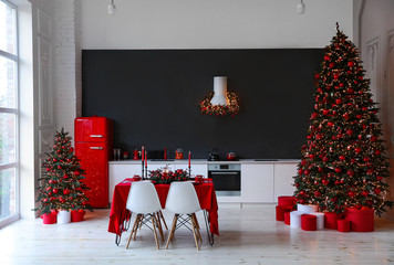 Stylish kitchen interior with festive table and decorated Christmas trees