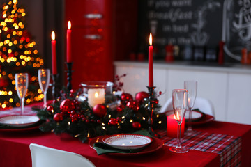 Table served for festive dinner and Christmas tree in stylish kitchen interior