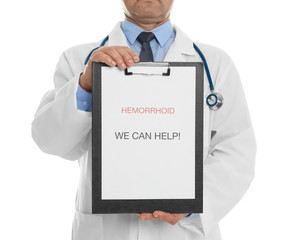Doctor holding clipboard with words HEMORRHOID WE CAN HELP on white background, closeup