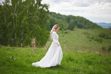 the bride walks in the field against the backdrop of the mountain