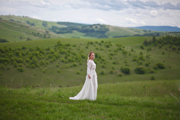 the bride walks in the field against the backdrop of the mountain