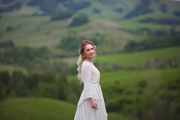 the bride walks in the field against the backdrop of the mountain