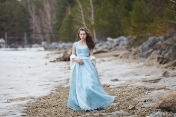 Fototapeta na wymiar A girl in a blue magnificent dress nullifies on the seashore.