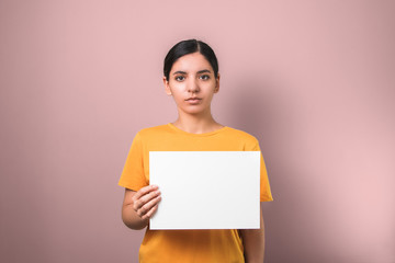 sad poor brunette woman in yellow shirt holding a white clean placard to add text