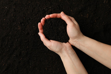Woman hold soil on soil background, top view