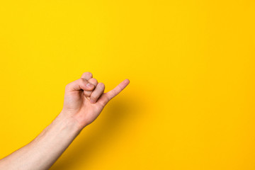 pinkie. keeping promise sign. little finger of male hand against yellow background with copy space...
