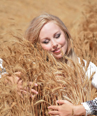 Beautiful blond caucasian woman in meadow with wheat.