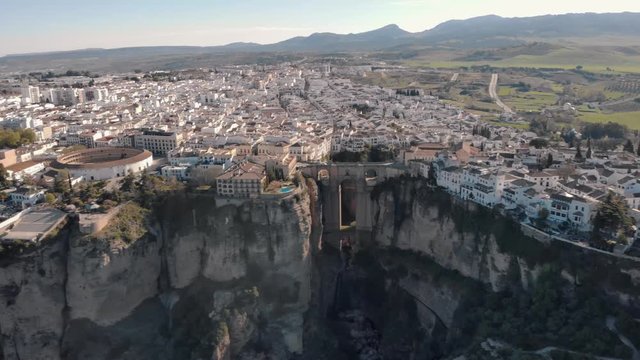 Aerial view of an ancient Spanish city Ronda in Andalucia. Drone flying over the famous bridge Puente Nuevo connecting the two parts of the Old Town, the Plaza de Toros (Bulls square) .