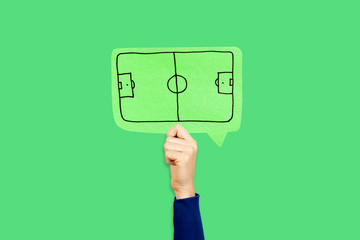 Hand holding a green soccer/football field speech bubble on green background. Business strategy, training, tactic concept.