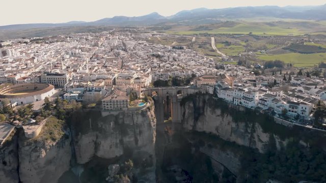 Aerial view of an ancient Spanish city Ronda in Andalucia. Drone flying over the famous bridge Puente Nuevo connecting the two parts of the Old Town, the Plaza de Toros (Bulls square) .