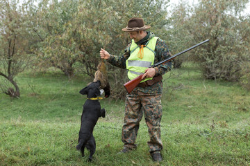 Hunting period, autumn season open. A hunter with a gun in his hands in hunting clothes in the...