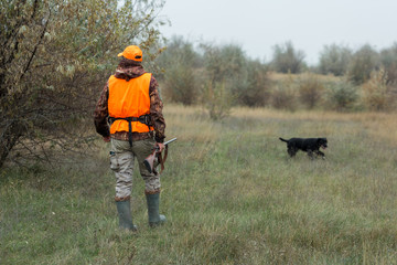 Hunting period, autumn season open. A hunter with a gun in his hands in hunting clothes in the...