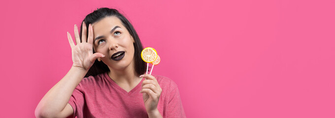 Portrait of lovely sweet beautiful cheerful woman with straight brown hair holding a lollipop near the eyes.