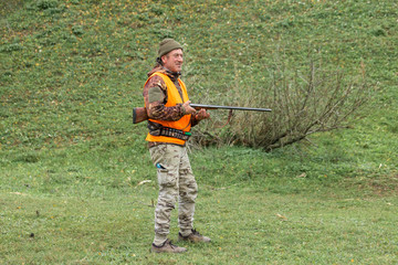 Hunting period, autumn season open. A hunter with a gun in his hands in hunting clothes in the...