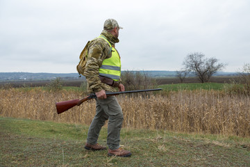 Hunting period, autumn season open. A hunter with a gun in his hands in hunting clothes in the...