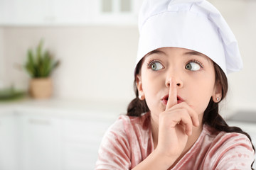 Cute little girl wearing chef hat in kitchen