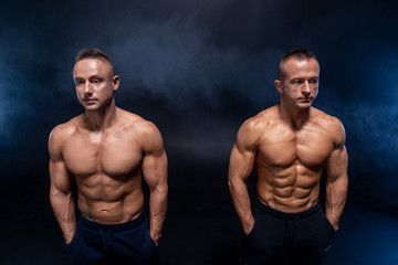 Two Muscular man isolated on the black background. Strong male naked torso abs