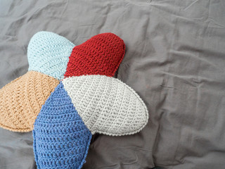 Closeup hand made multicolored yarn knitted pillow in the shape of a starfish on a gray background