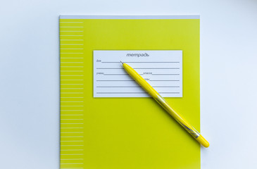 Top view of front page of green pupils copybook with form to sign in: name, surname, grade, etc. with yellow pen on white background. Concept of education, minimalism.